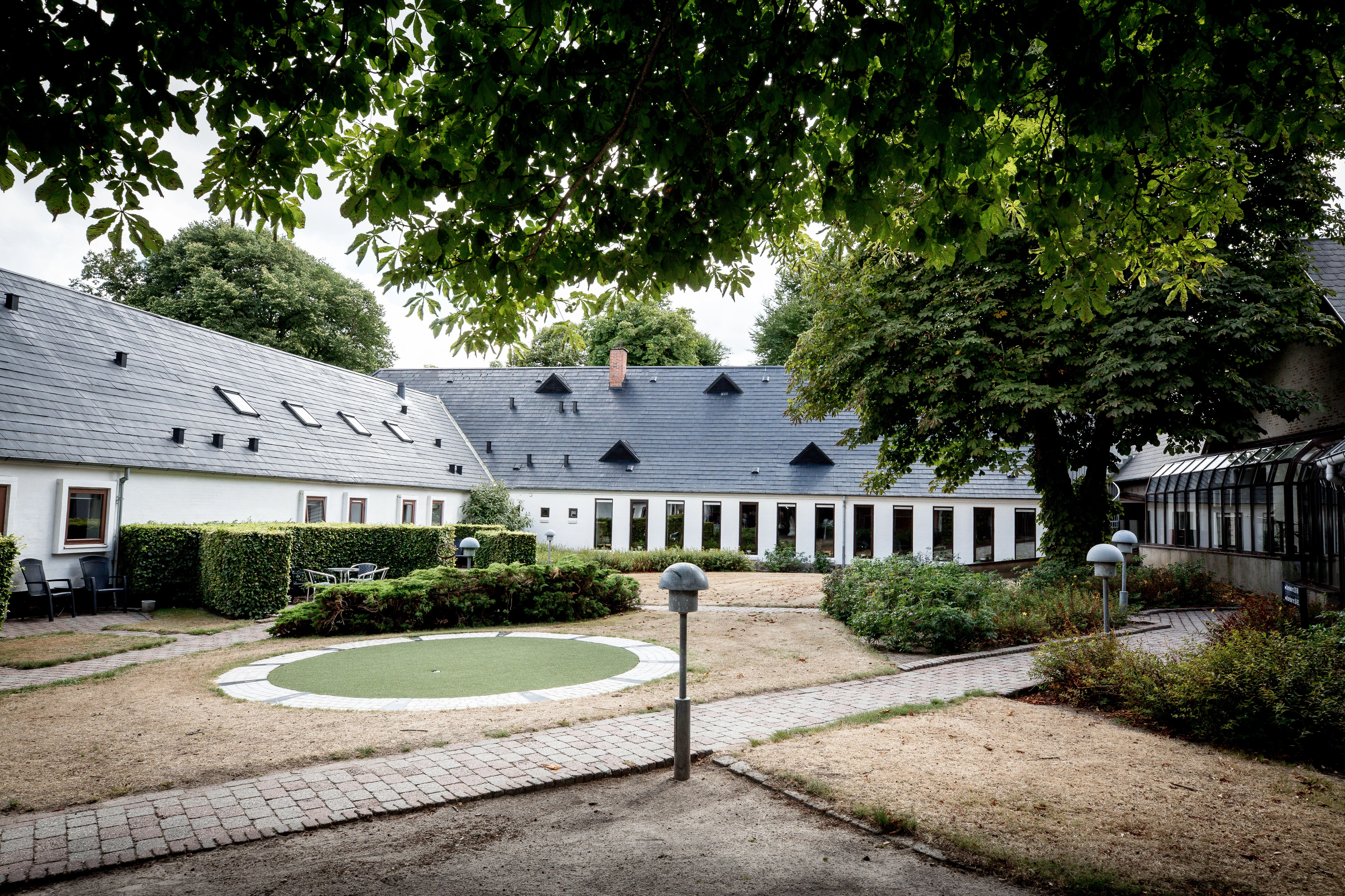 Hof des Verbandshauses unter Kastanien mit Rundrasen und weißen Gebäuden